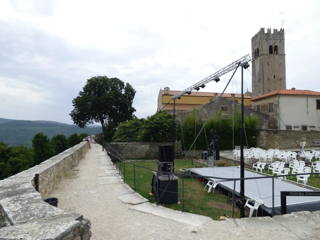 Scène et rangées de chaises blanches montées au pied de la tour de Motovun