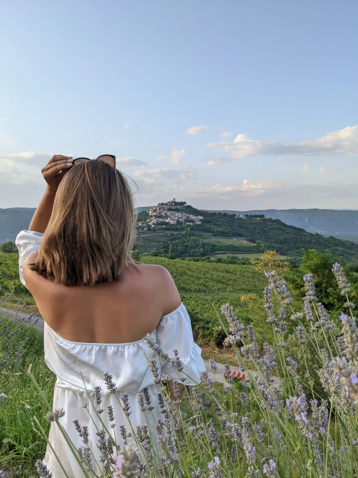 Femme en robe blanche dans la lavande face au village perché de Motovun
