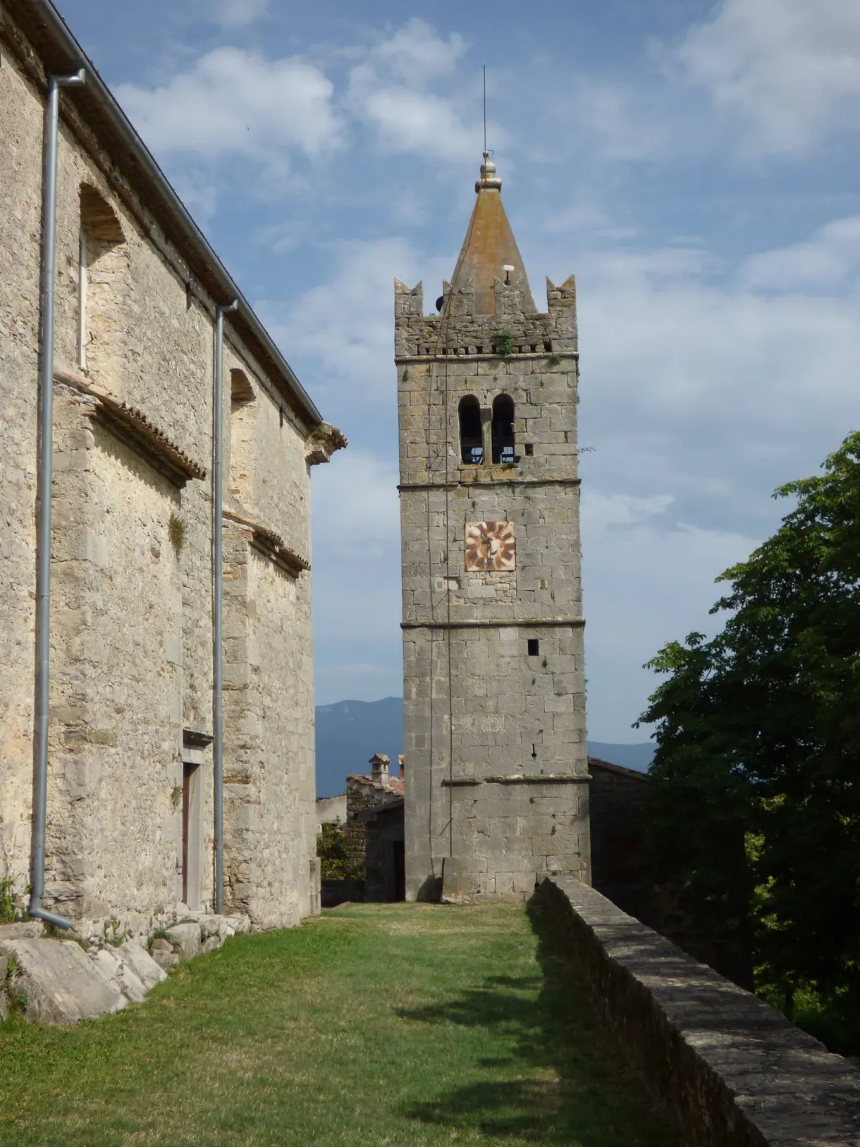 Église de pierre et clocher à horloge de Hum sur une pelouse rase