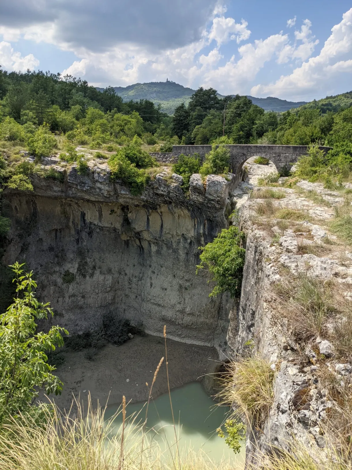 Gorge rocheuse et petite retenue d'eau verte au pied des falaises
