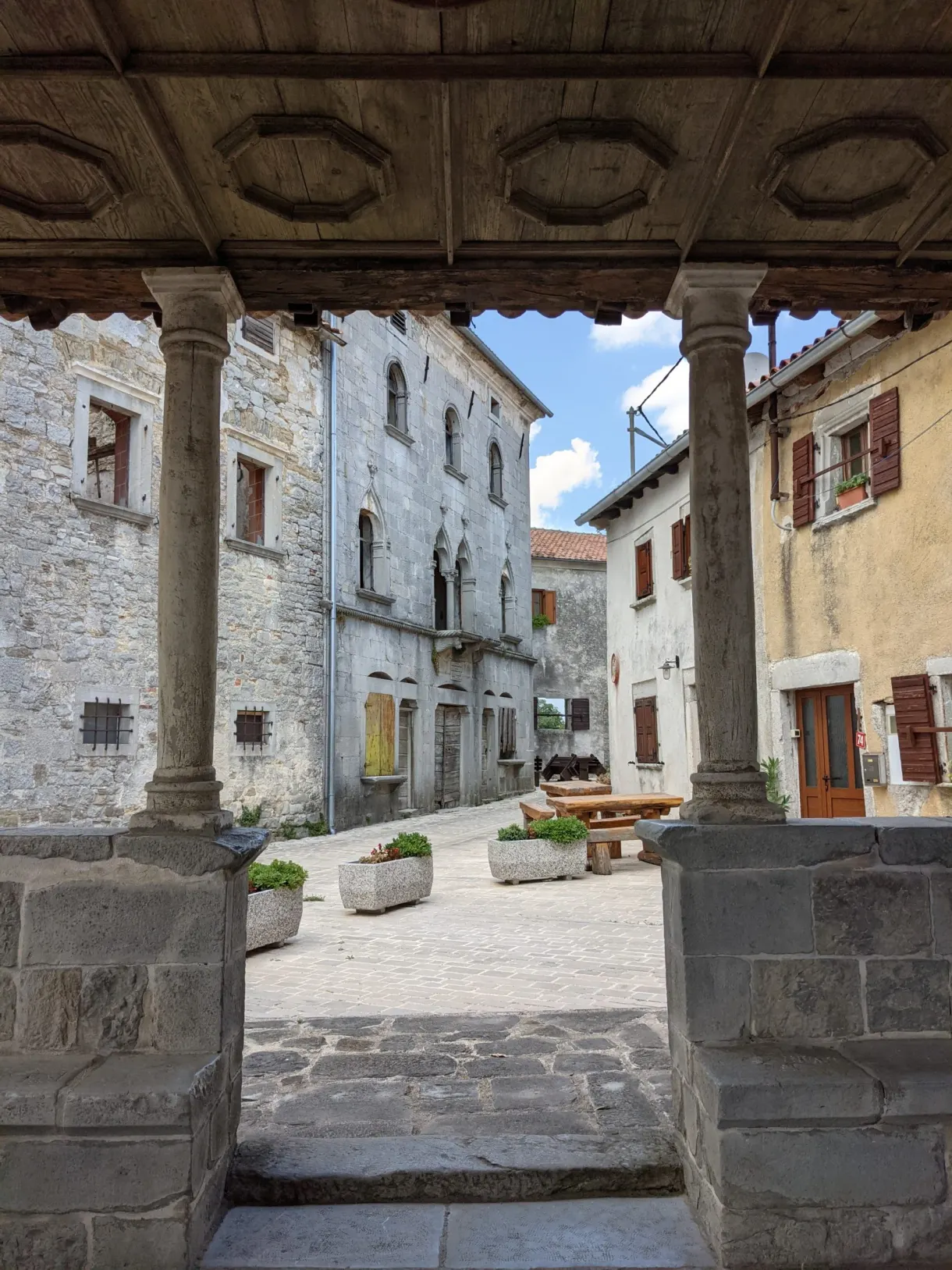Place de village encadrée par la charpente d'une loggia à Gračišće
