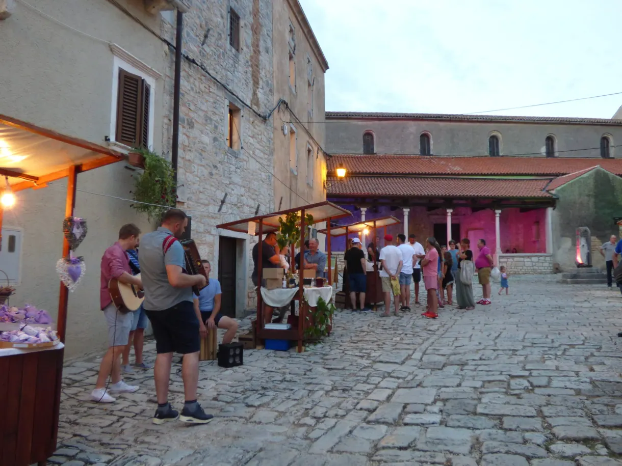 Stands illuminés et promeneurs dans une rue de Sveti Lovreč le soir