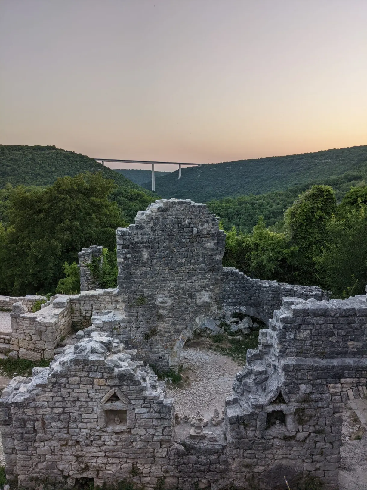 Murs d'église écroulés de Dvigrad au crépuscule, viaduc au loin
