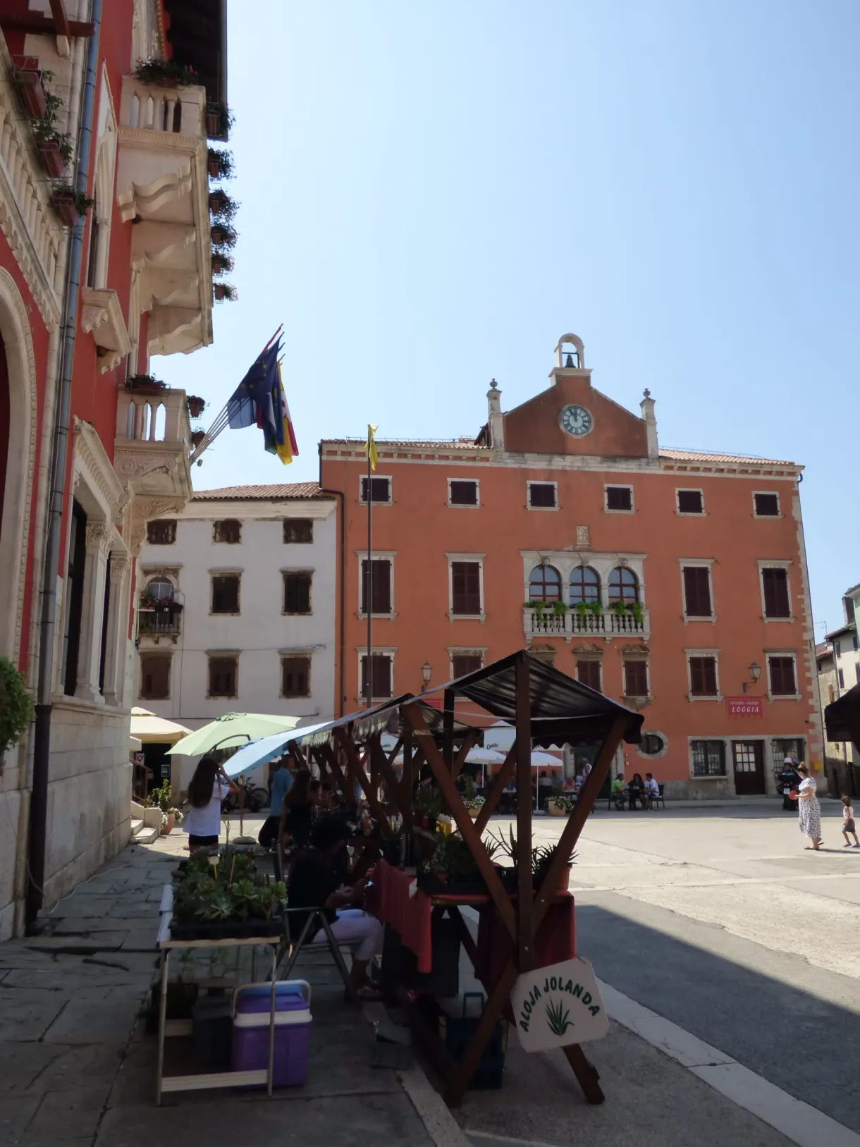Étal de marché sous auvent devant le palais rouge de Vodnjan