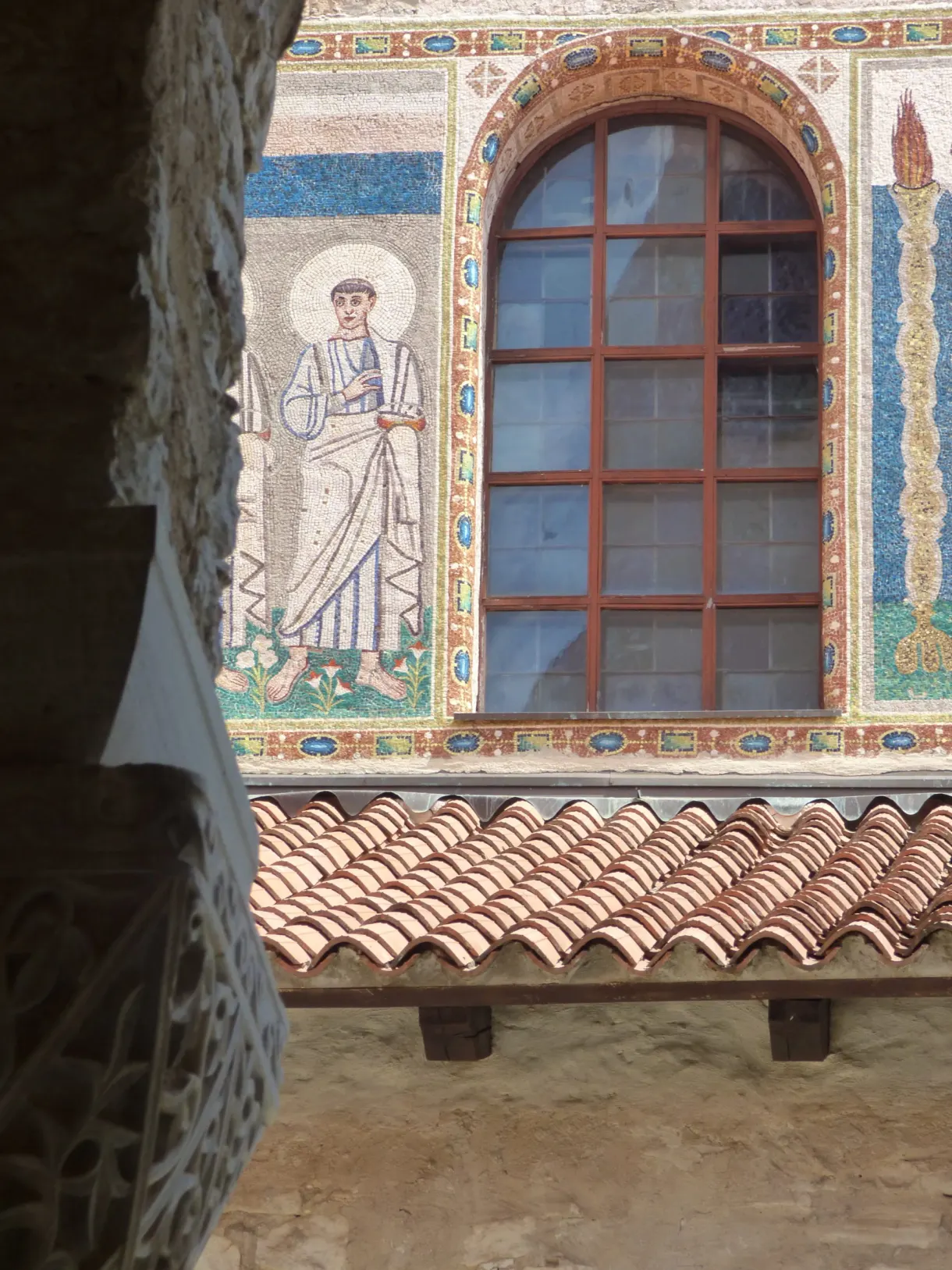 Mosaïque d'un saint autour d'une fenêtre en façade, au-dessus des tuiles