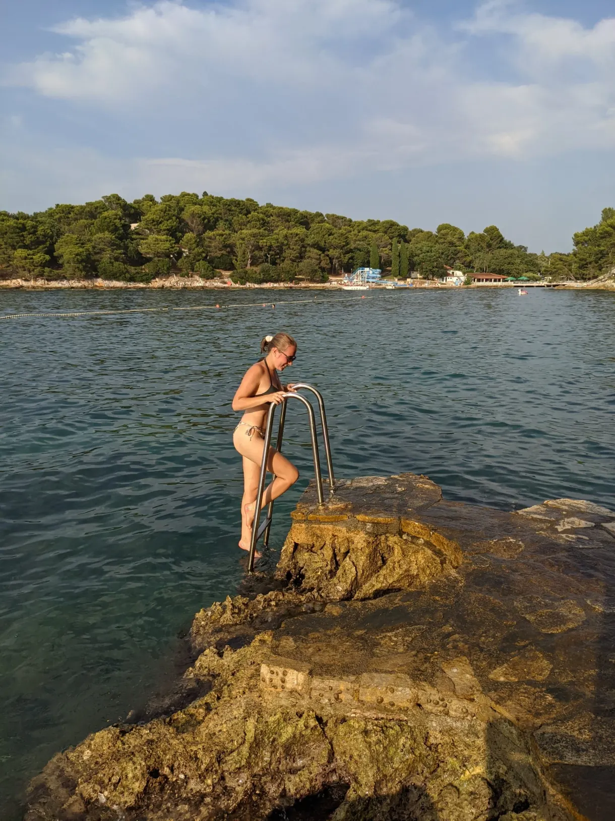 Baigneuse descendant à l'eau par l'échelle d'une crique rocheuse