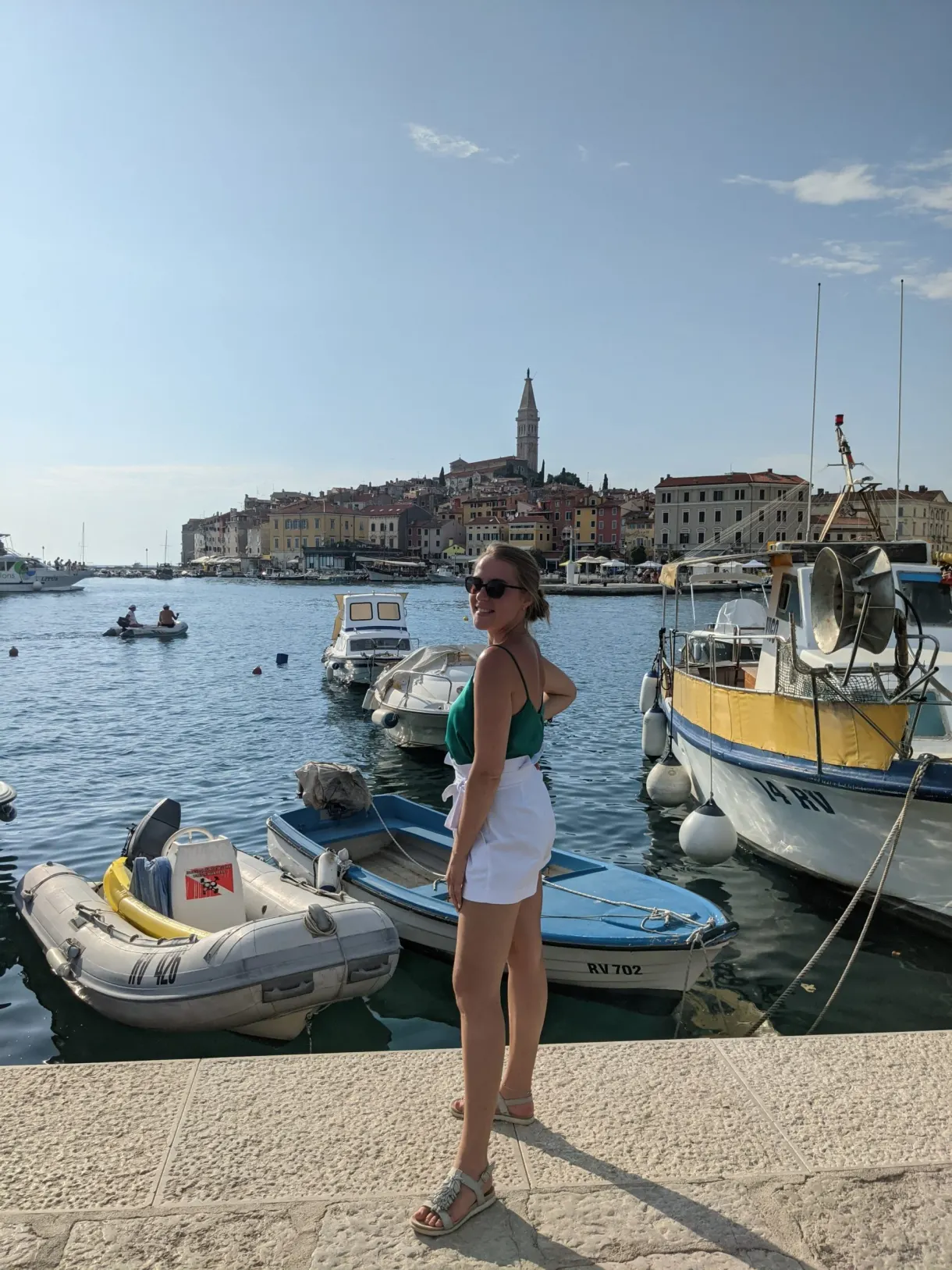 Femme sur le quai de Rovinj devant les barques et la vieille ville