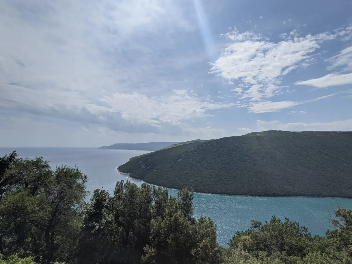 Baie arrondie et promontoire vus à travers les arbres depuis Plomin
