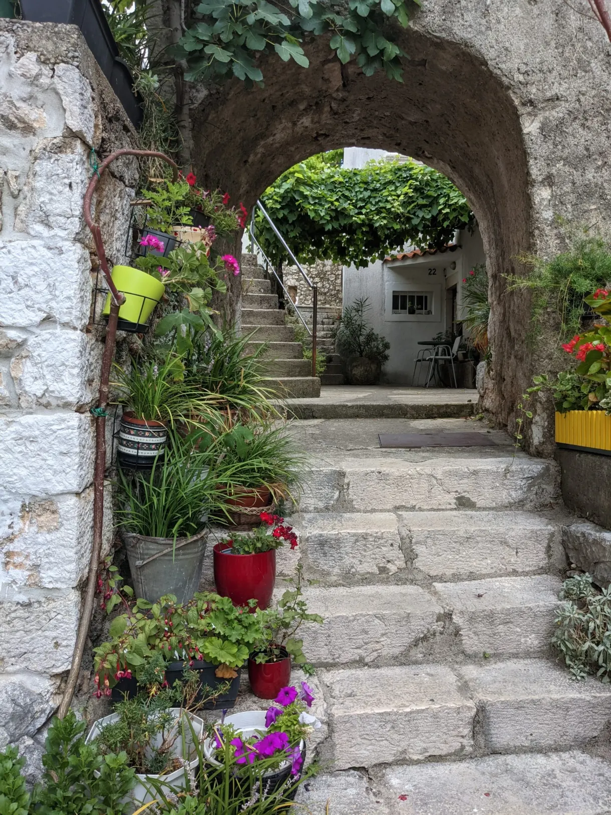 Passage voûté et marches bordées de pots de fleurs colorés, Brseč