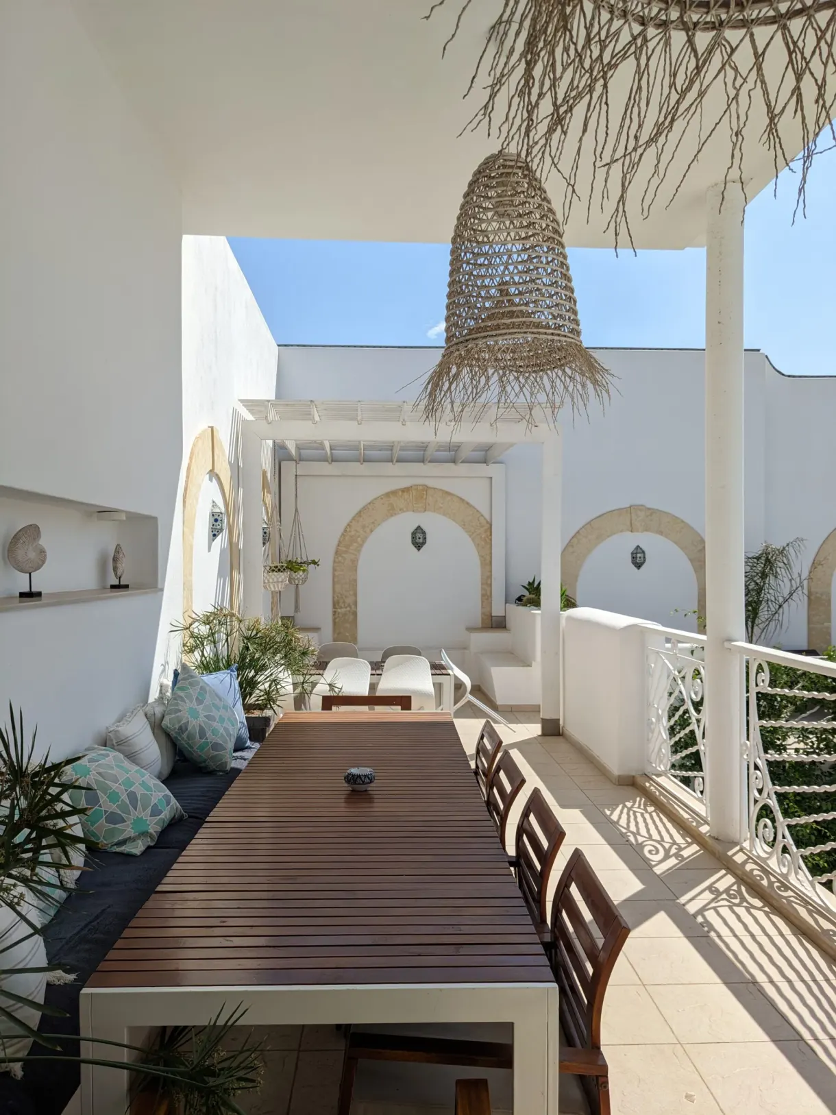 Terrasse ombragée de Dar Benti, grande table en bois et suspensions en osier