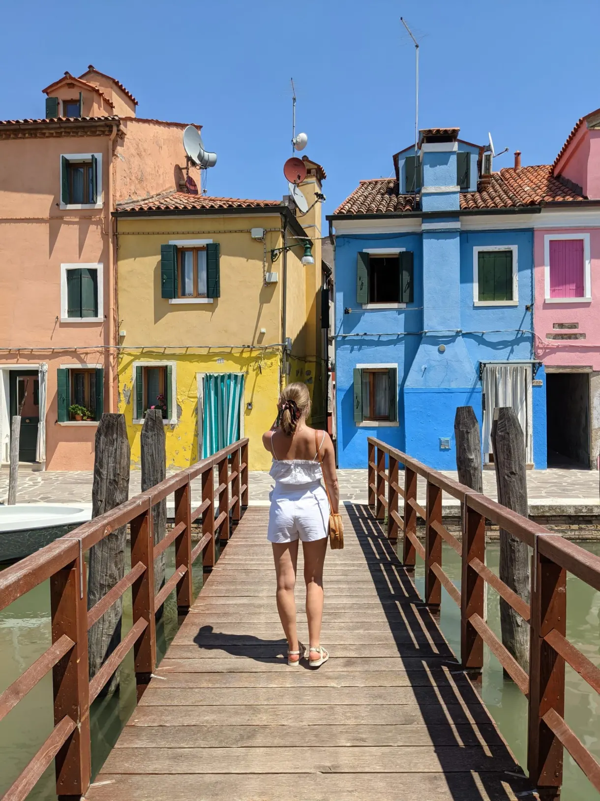 Crossing a wooden bridge between the colourful facades