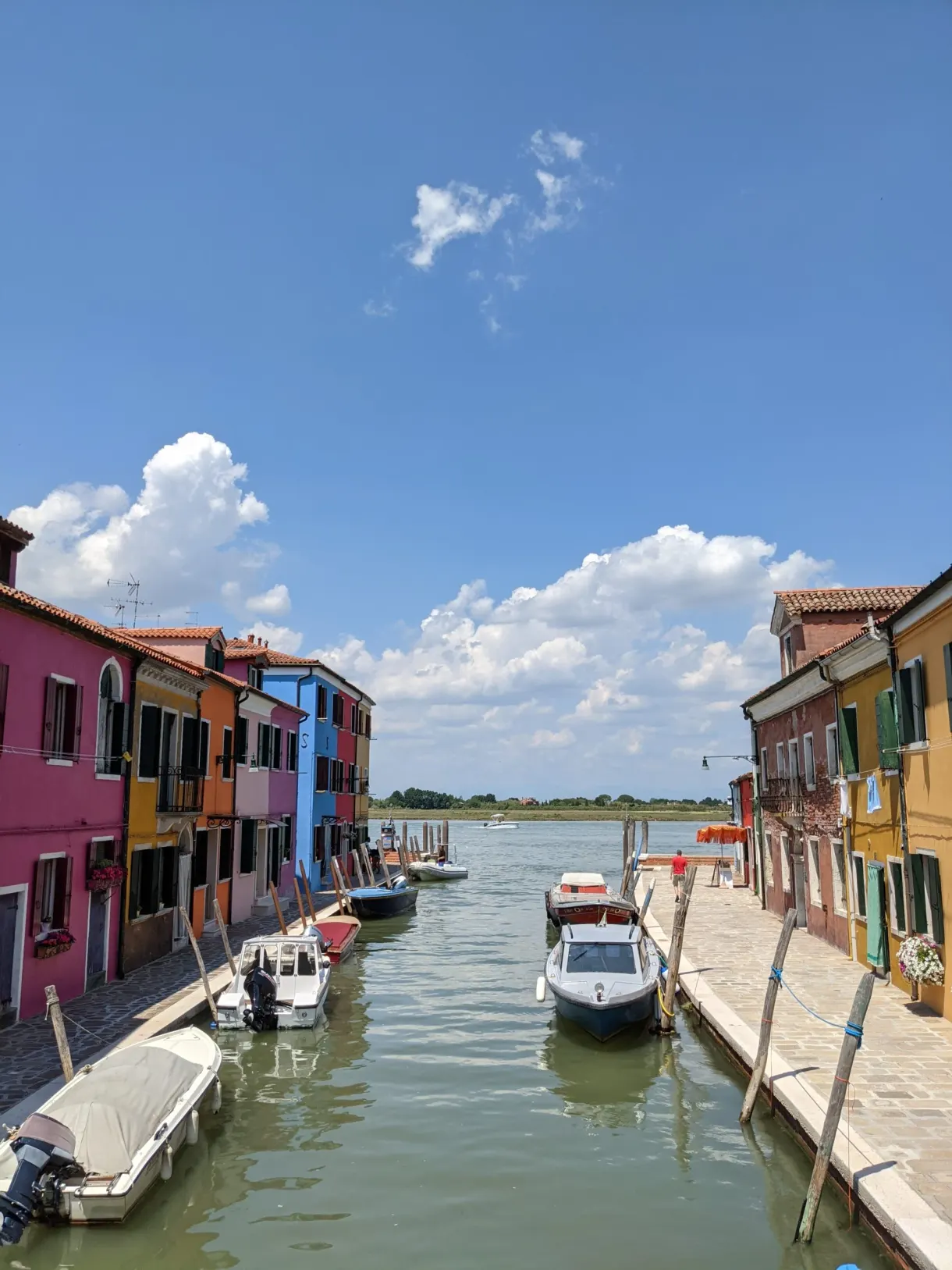 Wide Burano canal opening onto the lagoon, boats at the quay