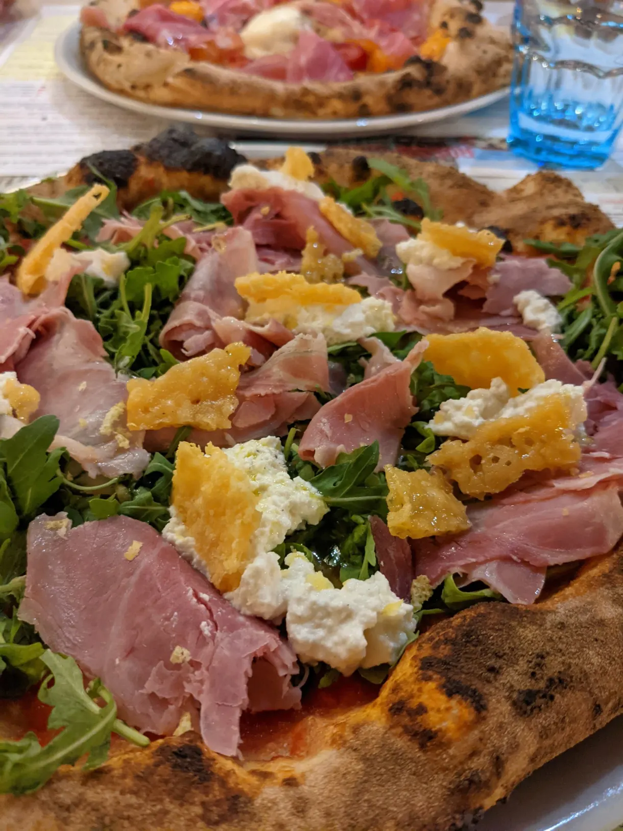 Pizza with cured ham, rocket and burrata in close-up