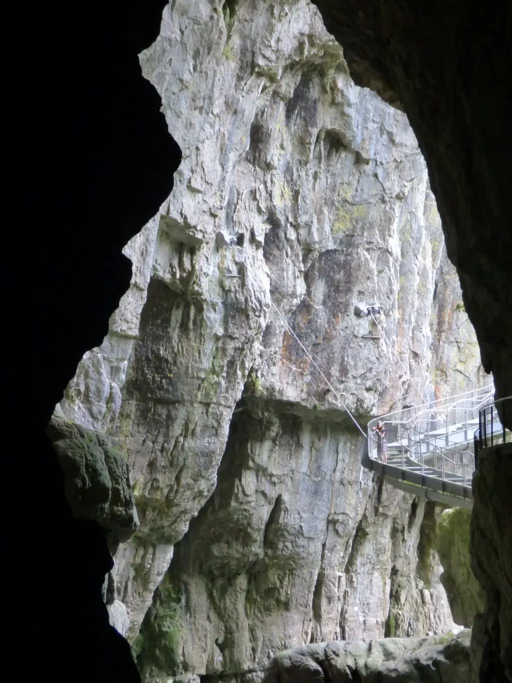 Haute paroi sombre longée d'un escalier suspendu