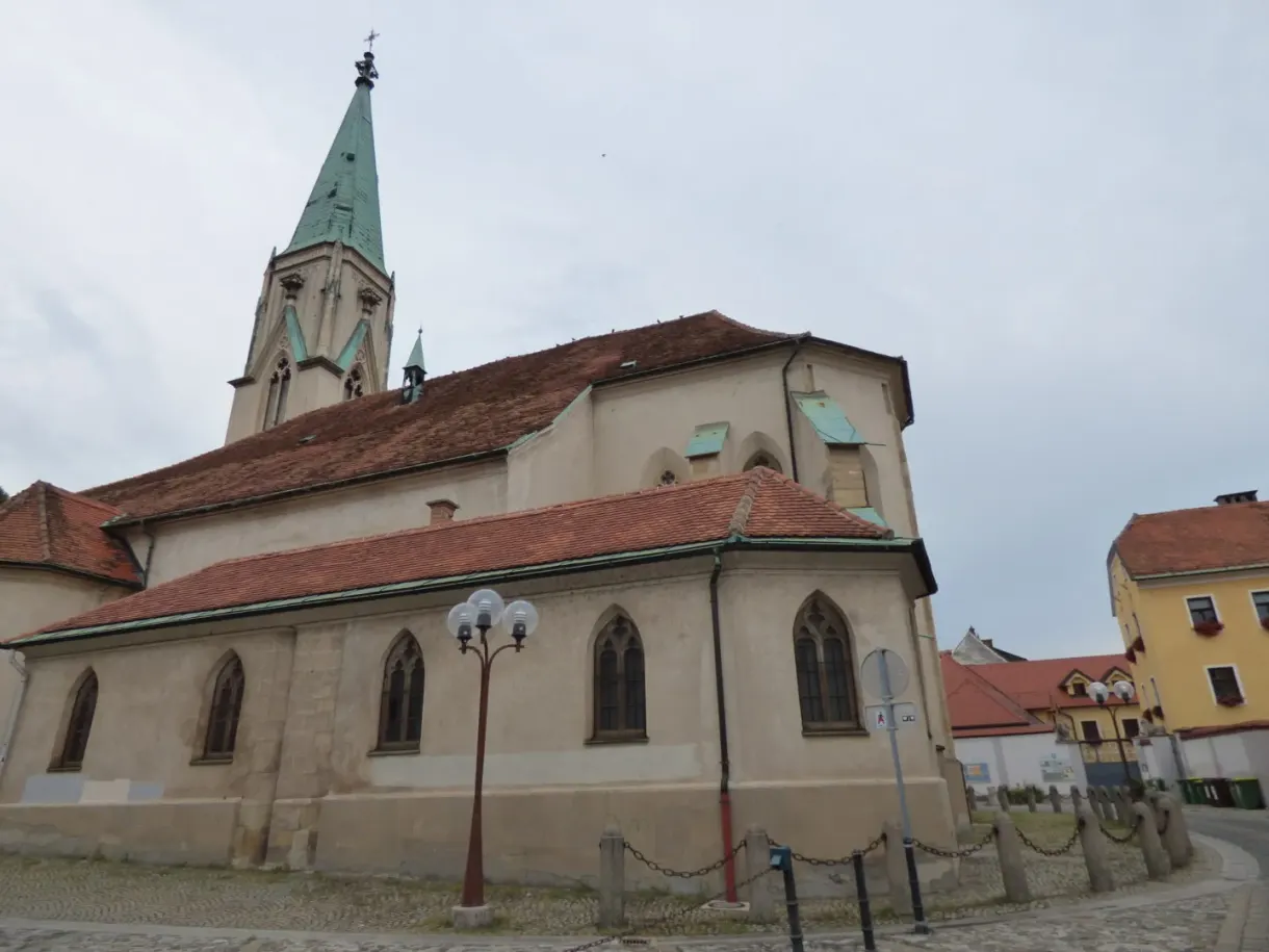 Église gothique au clocher vert pointu en bord de rue