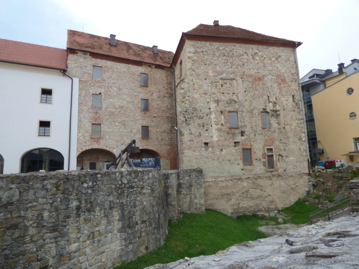 Bâtisse massive de pierre ocre dressée au-dessus d'un vieux mur