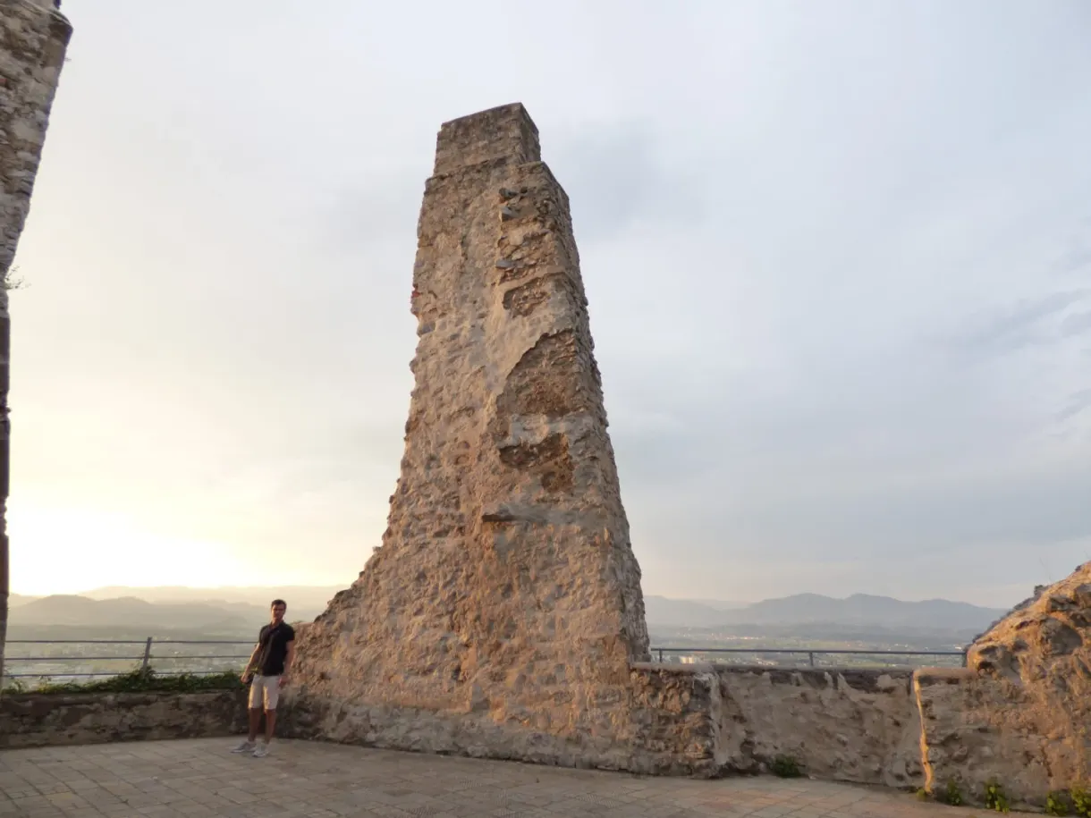 Pan de mur ruiné dressé contre le ciel, visiteur en contrebas