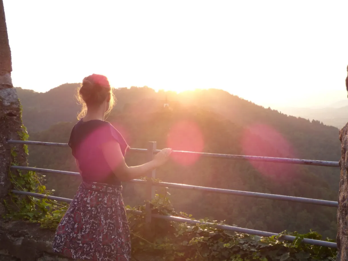 Femme à contre-jour devant le soleil couchant sur les collines