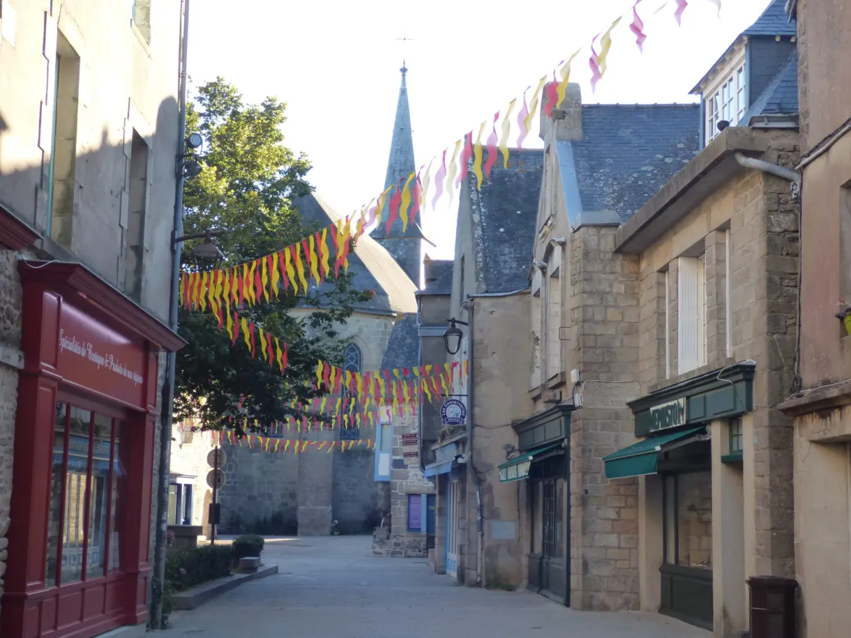 Red shopfront and bunting in a street leading to the bell tower