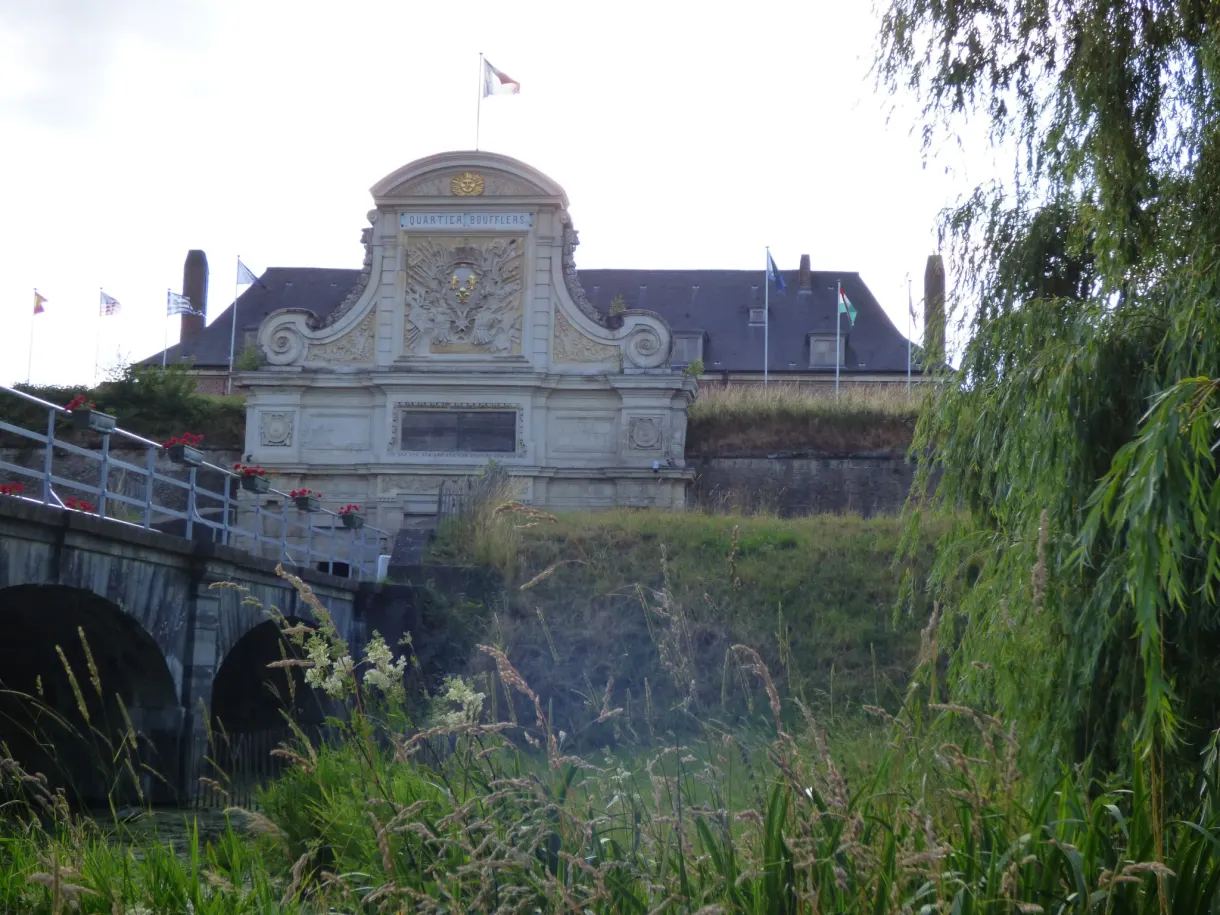 Façade blanche sculptée dominant un pont et une écluse