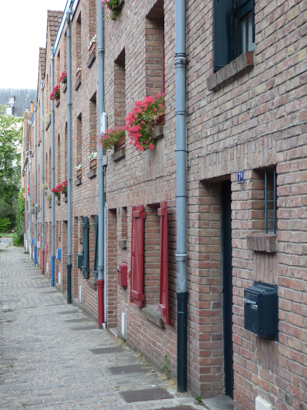 Ruelle étroite bordée de briques rouges et de portes colorées
