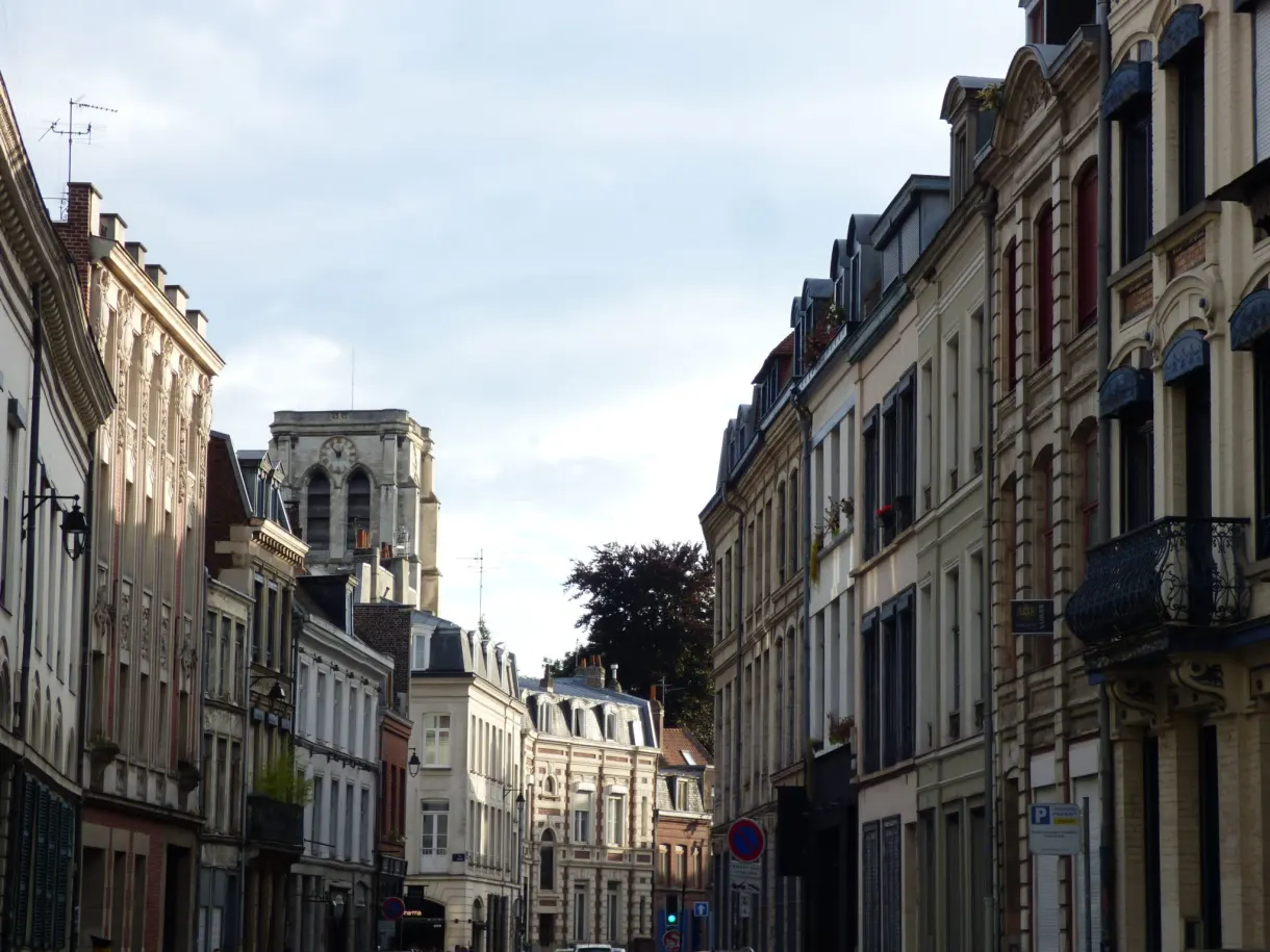 Rue en pente entre immeubles anciens et balcons de fer