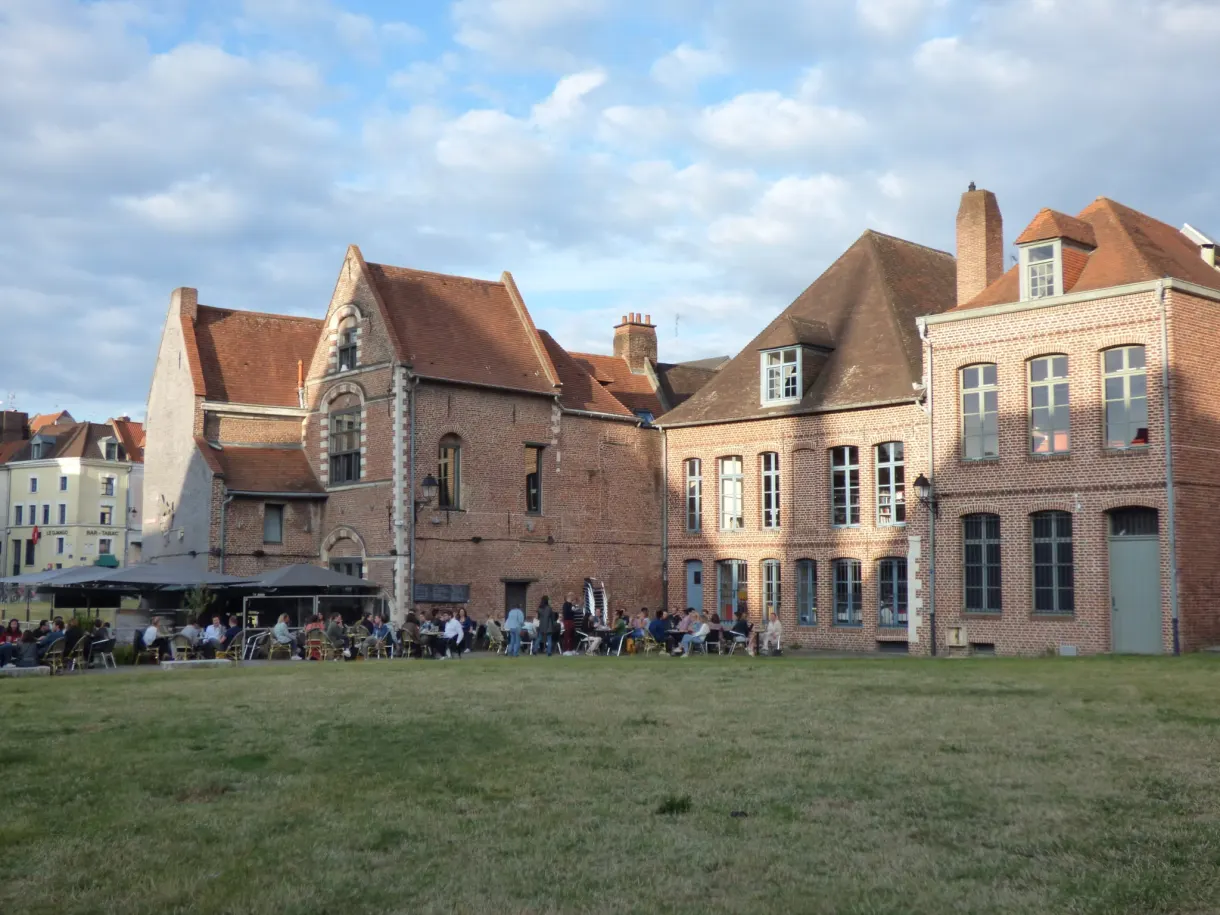 Terrasse bondée devant des maisons anciennes et une pelouse