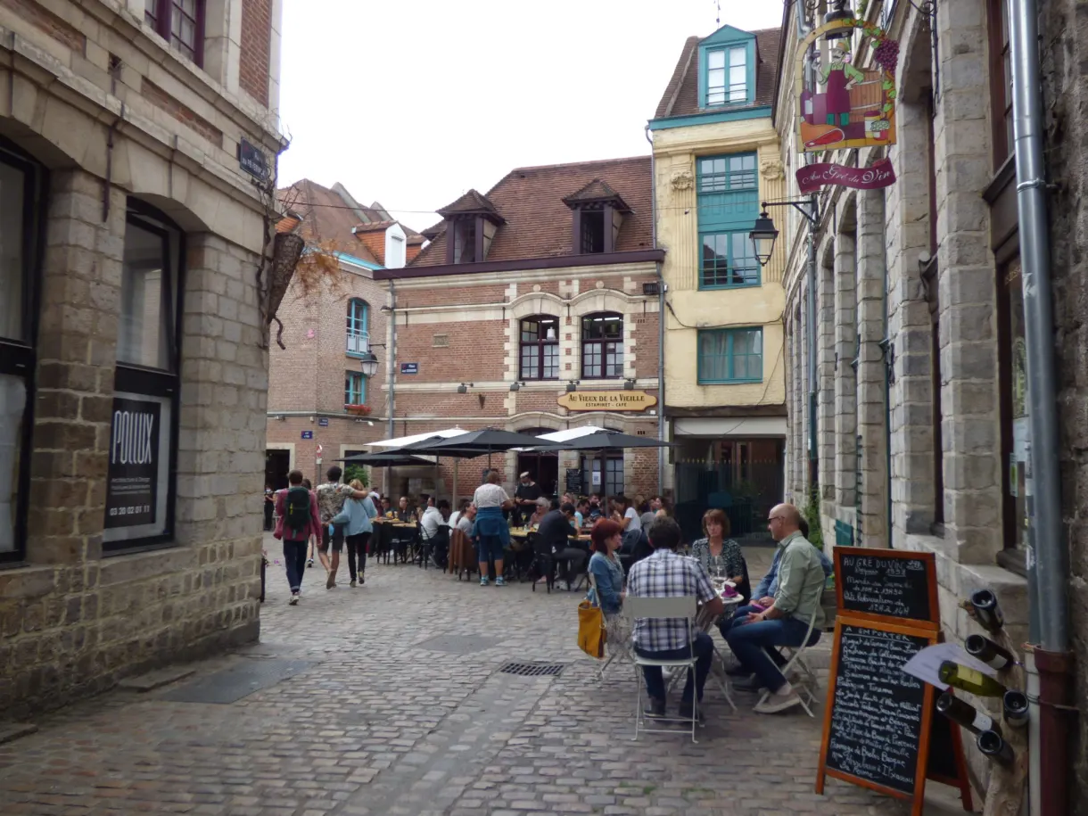 Terrasse de café animée dans une rue pavée en pente