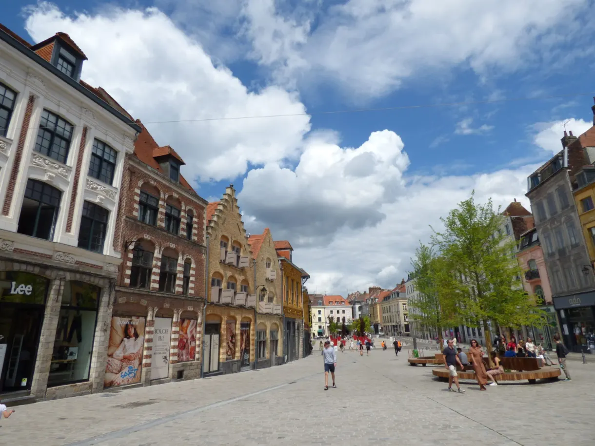 Place ouverte bordée de maisons à pignons, transats au centre