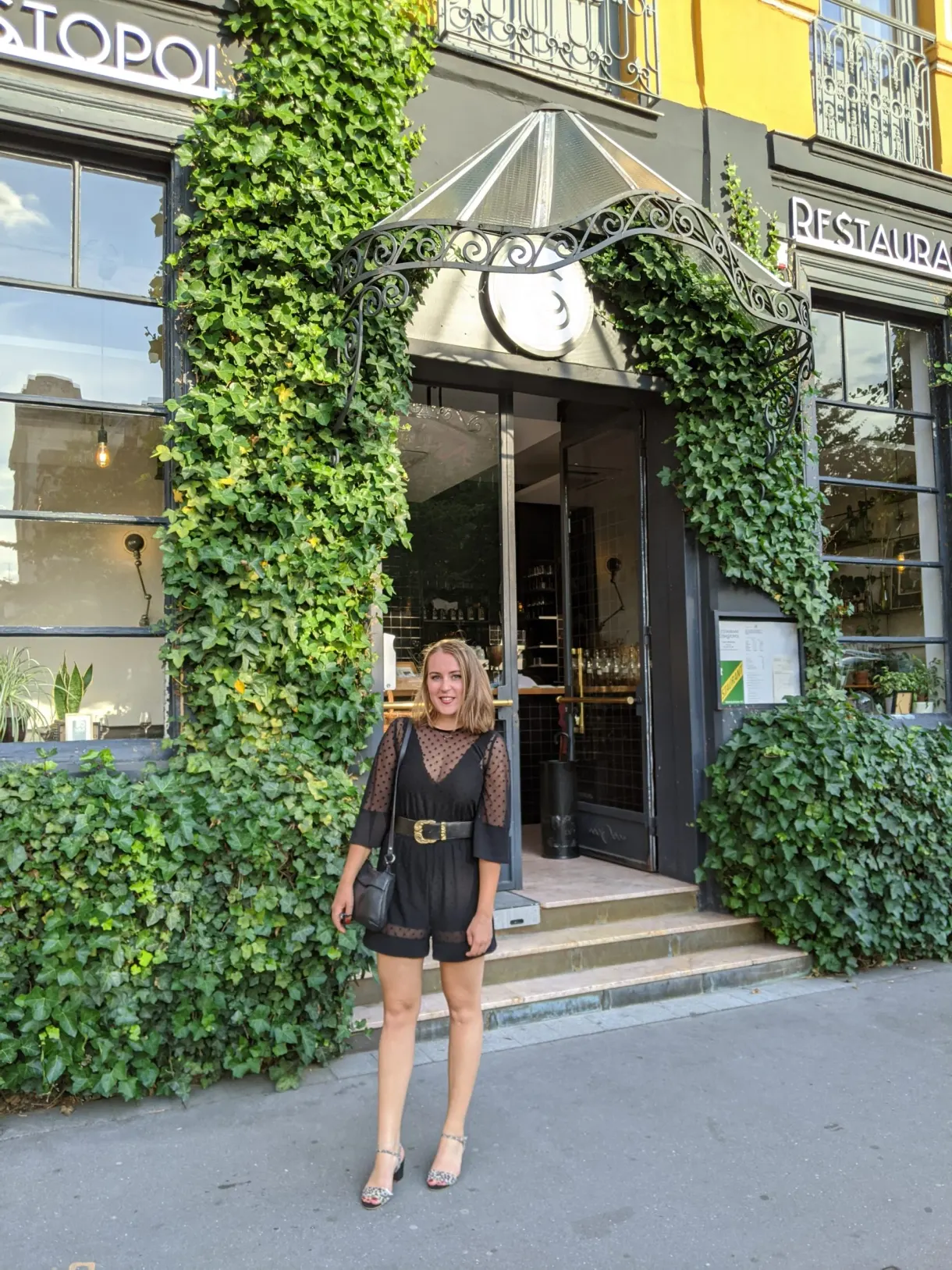 Femme devant l'entrée d'un restaurant couverte de lierre