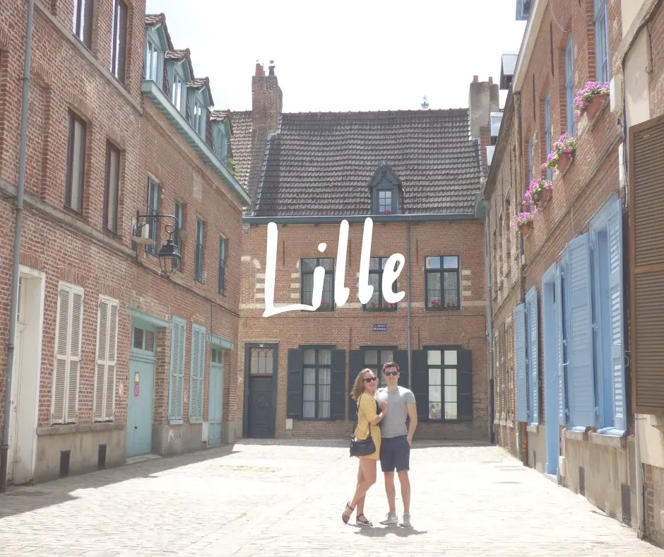 Couple posant dans une ruelle pavée aux volets bleus