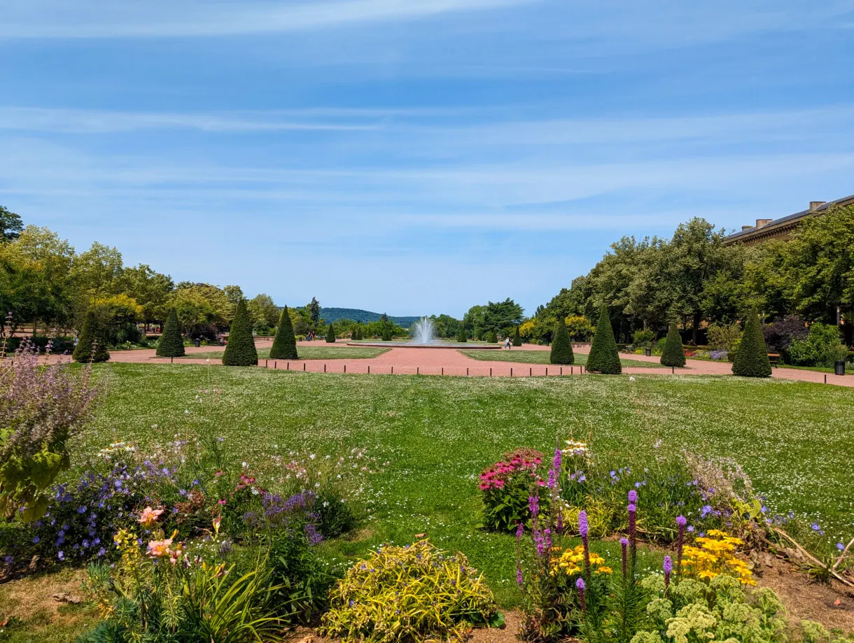 Vaste esplanade engazonnée avec bassin au fond et massif fleuri devant