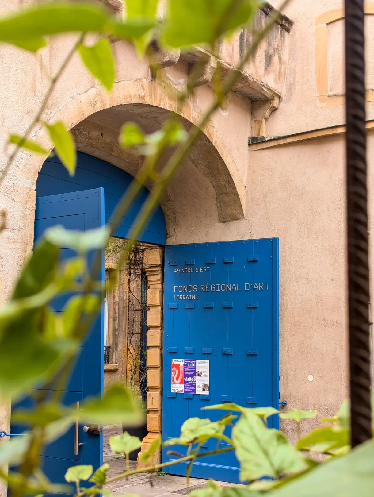 Porte cochère bleue du Fonds régional d'art contemporain, feuillage au premier plan
