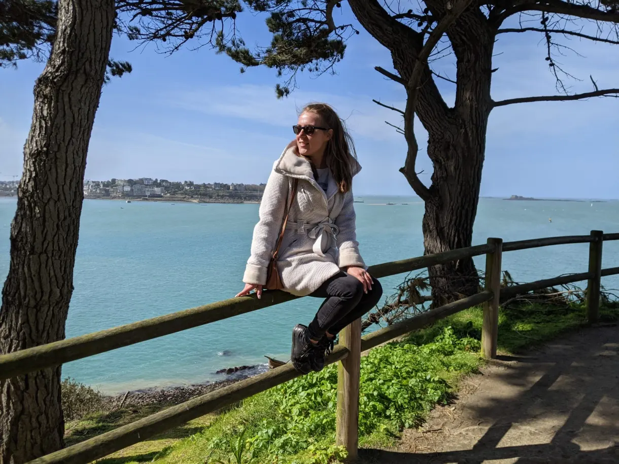 Voyageuse assise sur une barrière de bois sous les pins