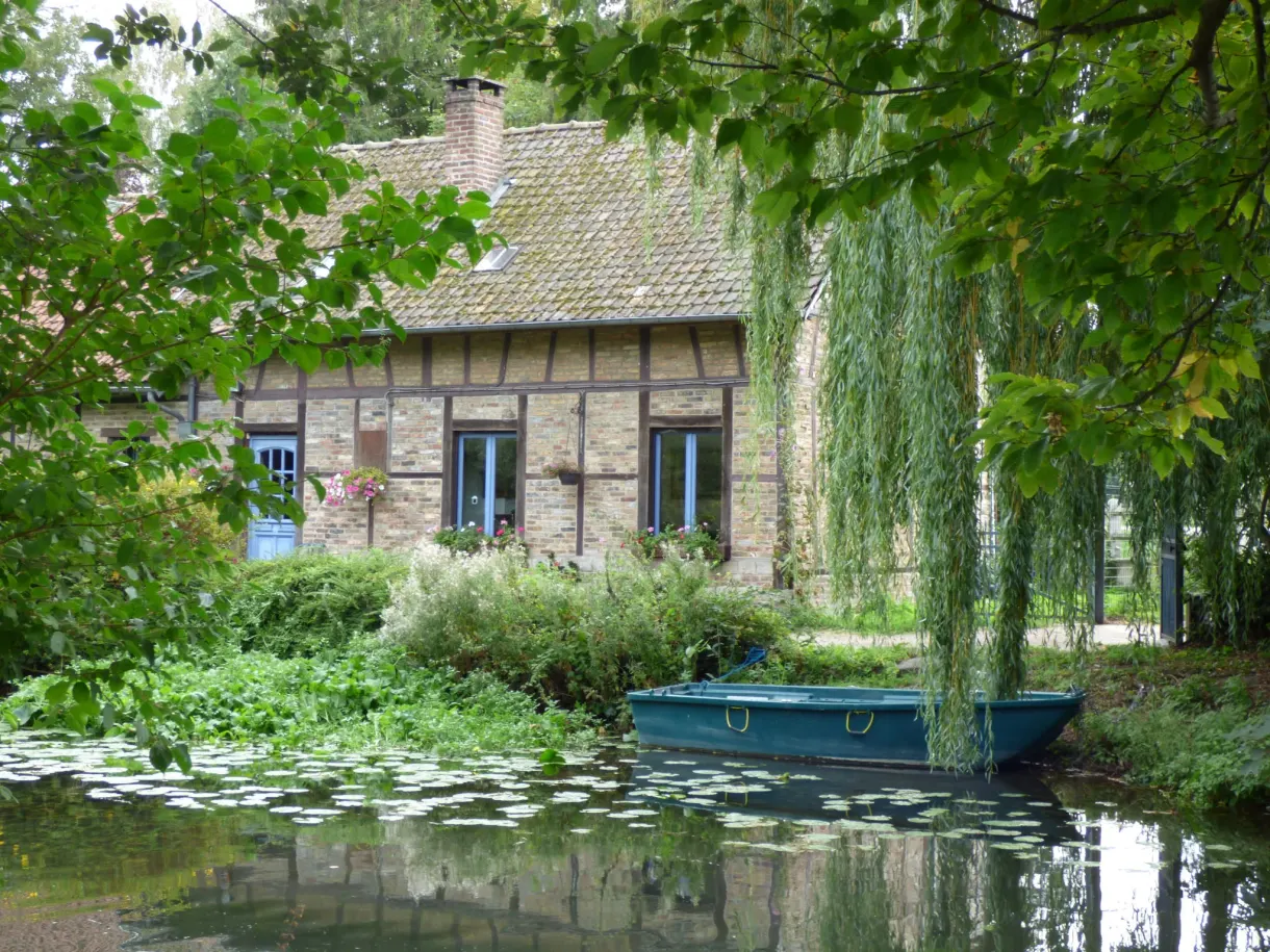 Maison à colombages au bord de l'eau et barque verte amarrée