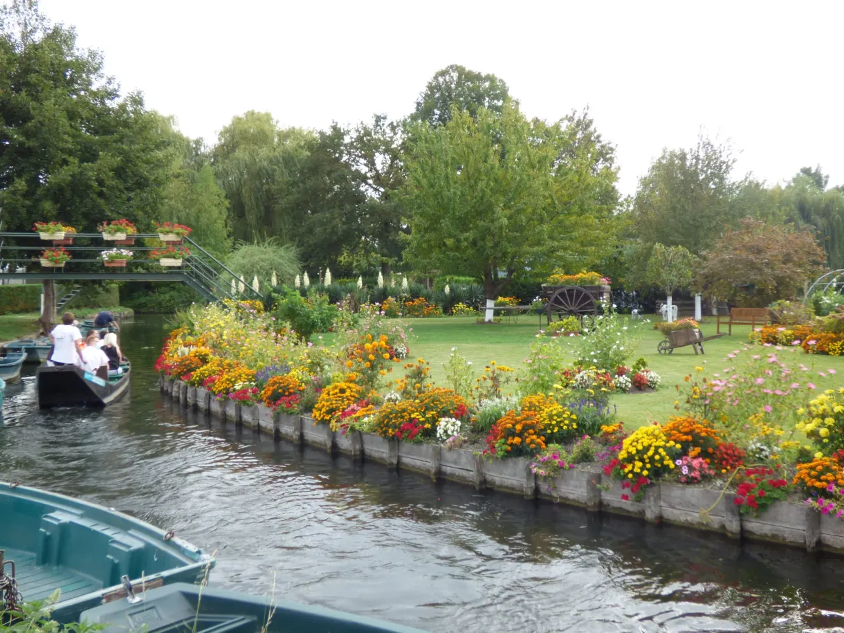 Barque de visiteurs longeant une parcelle fleurie des hortillonnages