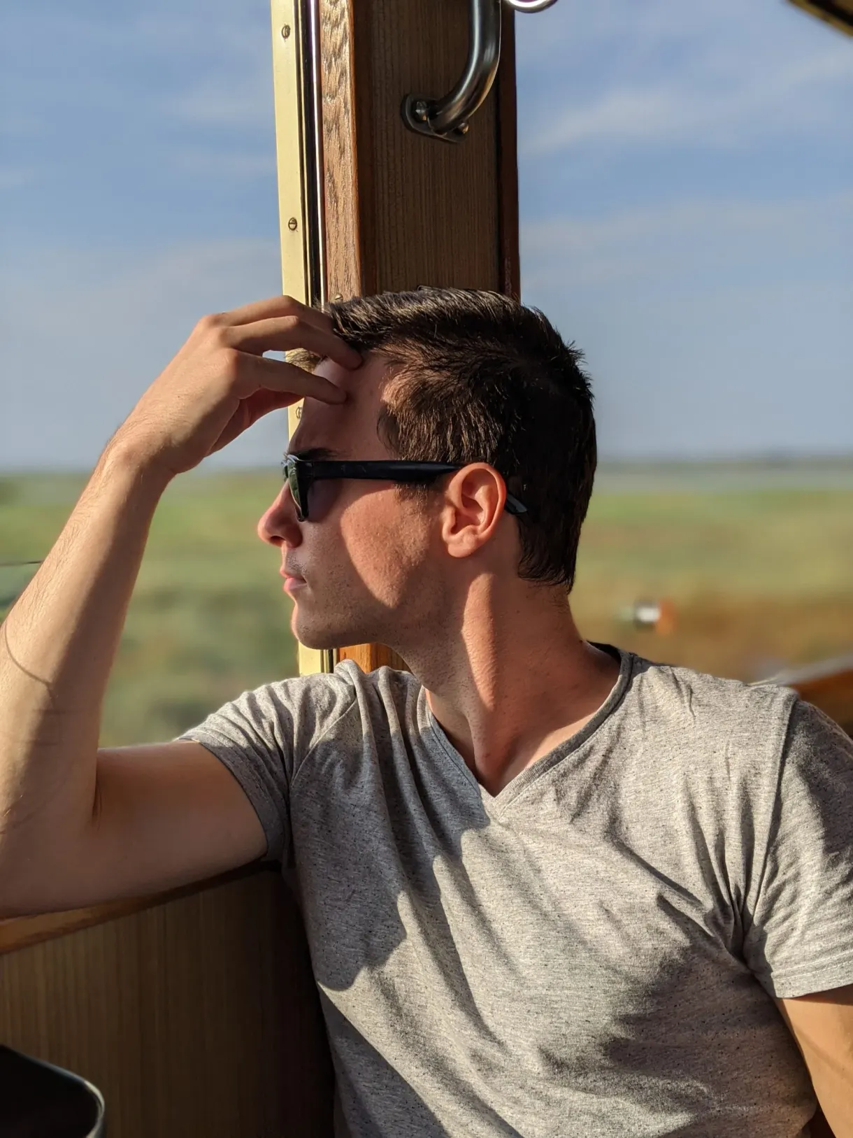 Voyageur accoudé à la fenêtre du wagon, lunettes de soleil