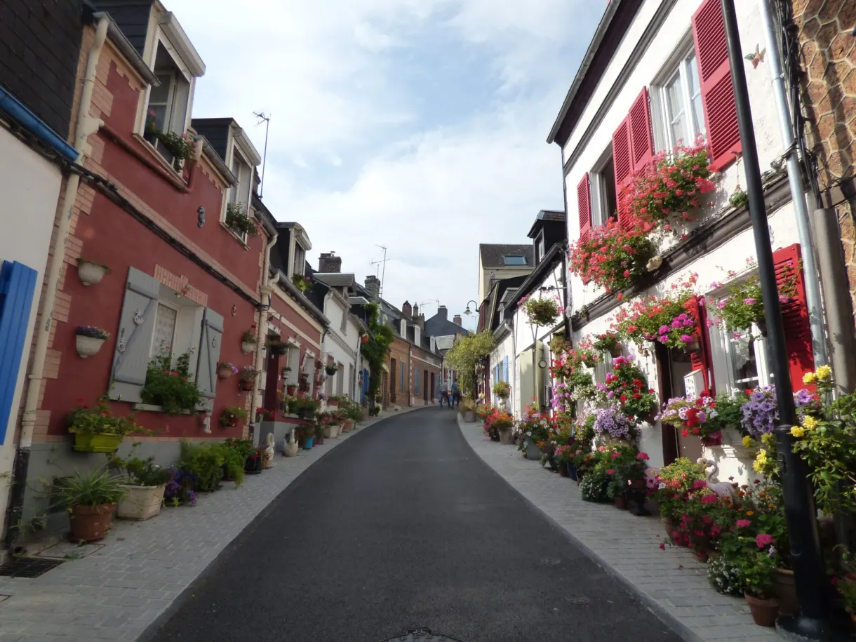 Ruelle en pente bordée de maisons fleuries aux volets rouges