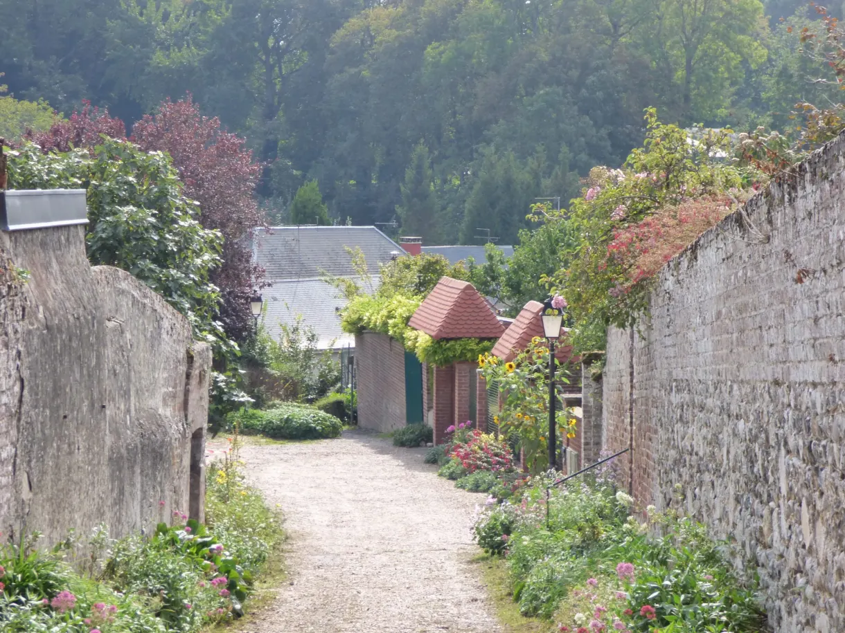 Sentier entre deux hauts murs de pierre couverts de fleurs
