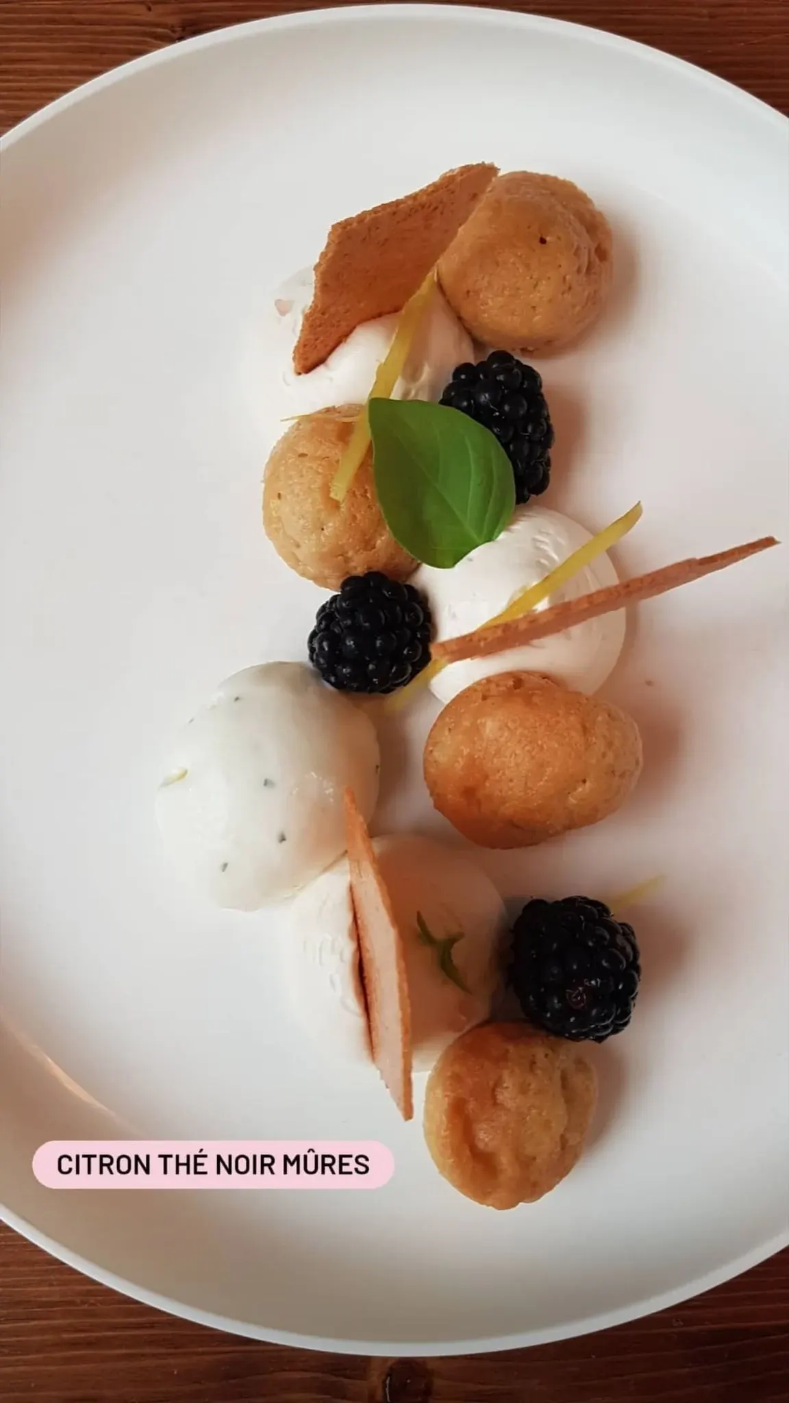 Dessert au citron, thé noir et mûres dressé sur assiette blanche