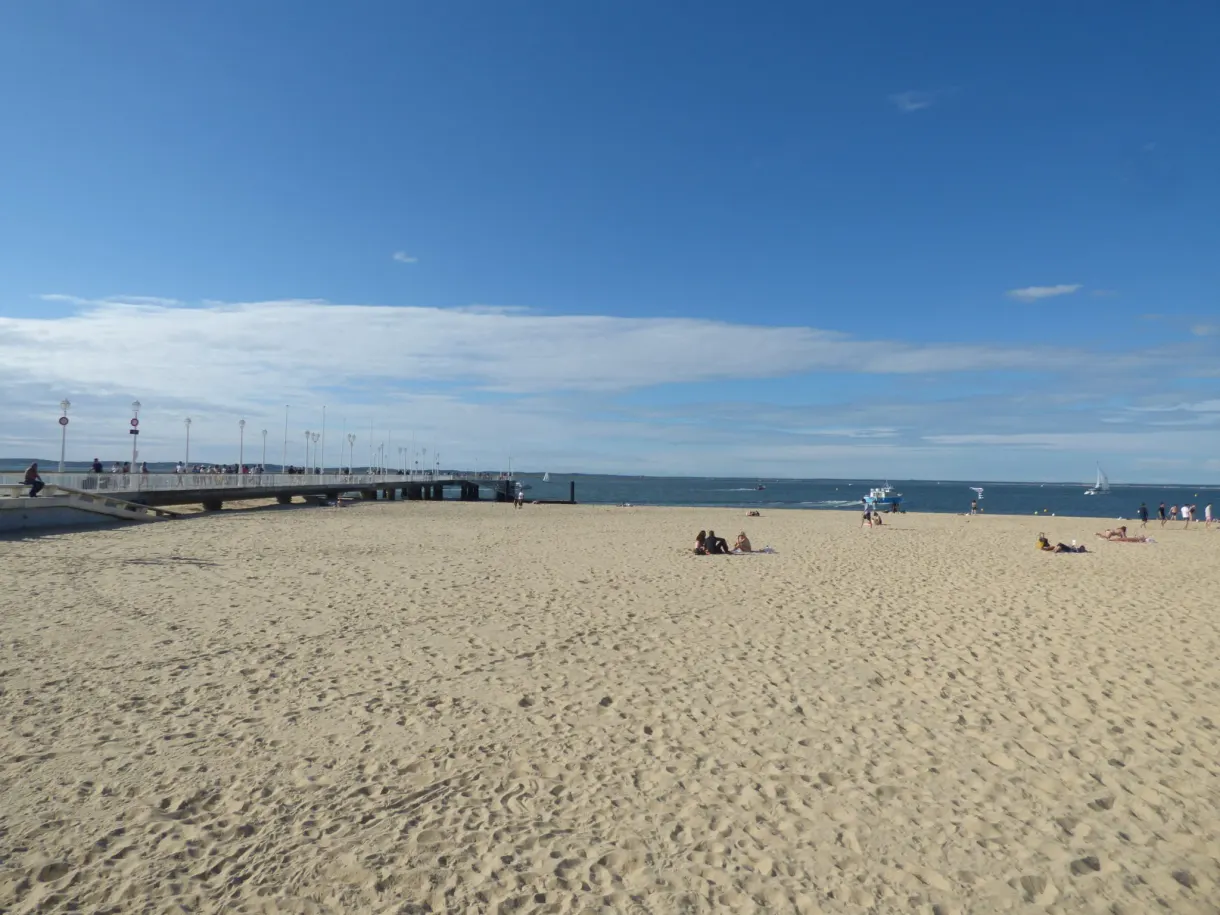 Longue plage de sable et jetée sous un ciel voilé