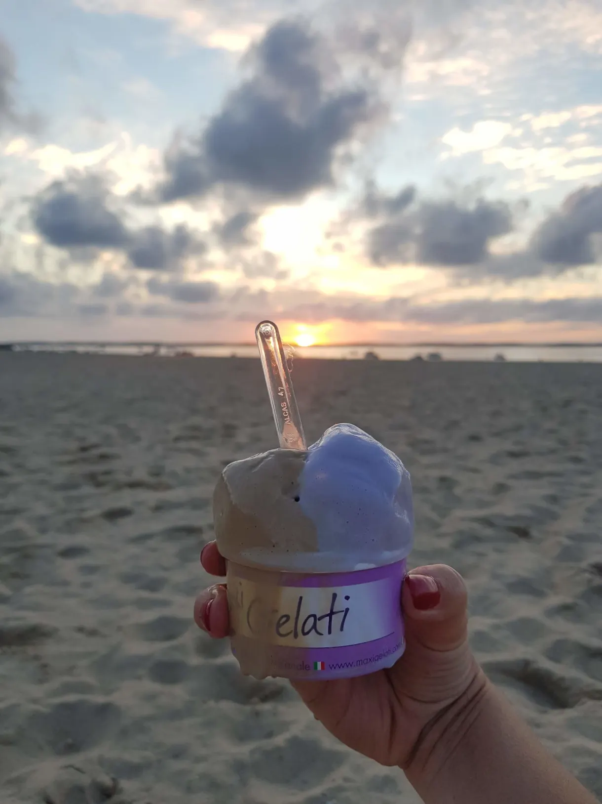 Pot de glace tenu face au coucher de soleil sur la plage