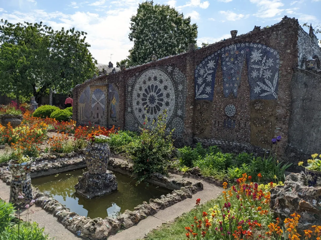 Bassin et parterres fleuris devant un mur de mosaïque